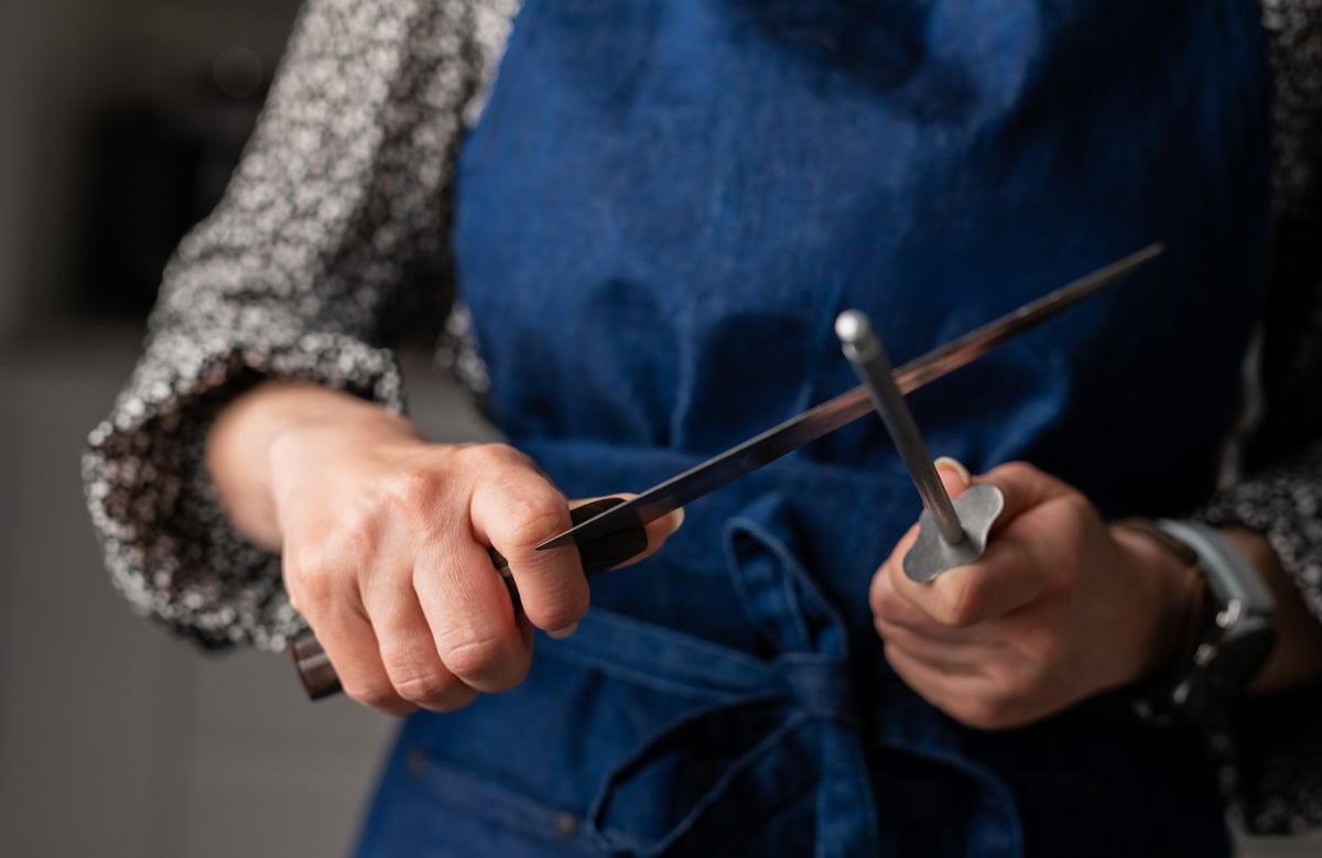 Close-up of hands hand sharpening a knife in a kitchen