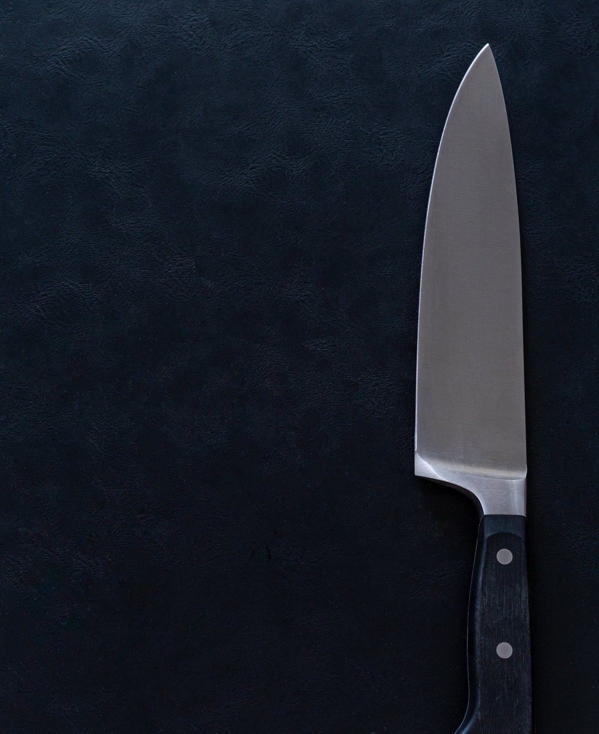 A sharp stainless steel kitchen knife with a black handle
